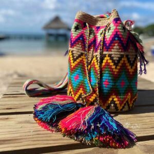 Ręcznie pleciona, egzotyczna i kolorowa torba na lato! Ta piękna etniczna torebka worek została wykonana przez artystkę z plemienia Wayuu na półwyspie la Guajira w północnej części Kolumbii. Matyzowane Mochile Wayuu to najnowszy trend wsród torebek Wayuu. Do przygotowania tła torby wykorzystuje się podwójną biało-beżową nić a wzory mogą być utkane nawet z SIEDMIU rożnych kolorów! Czas wykonania jednej torby to ok 2 tygodnie i tkana jest na szydelku tylko przez jedną artystkę. Bardzo lekka, wytrzymała i wygodna w noszeniu. Ta kolorowa ręcznie tkana etniczna torebka worek to idealny dodatek w stylu boho, który podkreśli twoją indywidualność i nada stylizacji wyjątkowego charakteru.